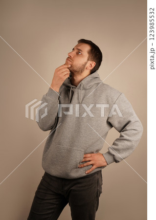 The gesture suggests focus and introspection. A man thoughtfully rests his hand on his chin, appearing deep in contemplation. His serious expression reflects a moment of deep thought. The gesture suggests focus and introspection. A man thoughtfully rests his hand on his chin, appearing deep in contemplation. His serious expression reflects a moment of deep thought. 123985532