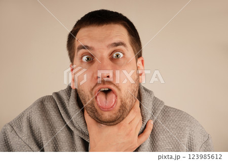 The discomfort on his face shows the urgency of the moment, as he struggles with breathing or a strong cough. A man grips his throat with his hand, mouth wide open as if he s choking or coughing. 123985612