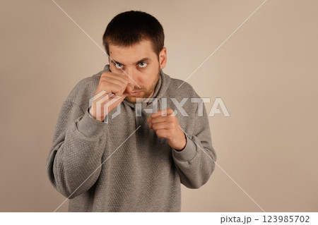 The man in an athletic hoodie adopts a boxing pose with tightly clenched fists. His stance exudes strength and focus. The scene suggests physical preparation and mental resilience. 123985702