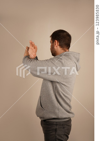 With arms crossed and fingers spread wide, a man creates a gesture of restriction or shielding. His open palms emphasize a defensive and assertive position. The image exudes caution and strength. With arms crossed and fingers spread wide, a man creates a gesture of restriction or shielding. His open palms emphasize a defensive and assertive position. The image exudes caution and strength. 123985830