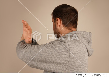 His open palms emphasize a defensive and assertive position. The image exudes caution and strength. With arms crossed and fingers spread wide, a man creates a gesture of restriction or shielding. His open palms emphasize a defensive and assertive position. The image exudes caution and strength. With arms crossed and fingers spread wide, a man creates a gesture of restriction or shielding. 123985832