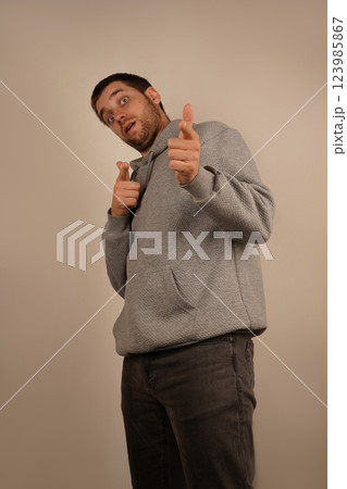 This action suggests clarity and decisiveness. The pose highlights confidence and direction. In gray athletic wear, the man uses his index fingers to point in one direction. This action suggests clarity and decisiveness. The pose highlights confidence and direction. In gray athletic wear, the man uses his index fingers to point in one direction. 123985867