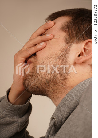 The man places his palm on his face, performing a facepalm gesture. This classic gesture expresses frustration, disbelief, or embarrassment. It s a universal sign of exasperation or regret. 123985872