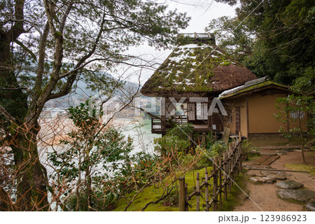 風光明媚な川の畔 雪の残る萱葺きの茶室のある風景 123986923
