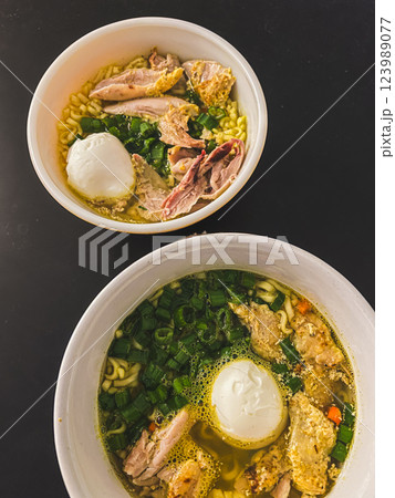Chicken noodle soup with egg in bowl, green onion and meat in Asian food style. Top view Chicken noodle soup with egg in bowl, green onion and meat in Asian food style. Top view 123989077