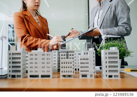 Asian architects and developers in a modern office collaborate using building models and digital tools Asian architects and developers in a modern office collaborate using building models and digital tools 123989136