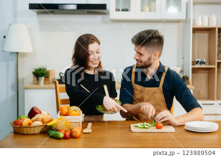 Discover a joyful couple preparing fresh vegetables, embracing healthy eating and teamwork in a vibrant kitchen 123989504