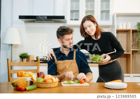 Discover a joyful couple preparing fresh vegetables, embracing healthy eating and teamwork in a vibrant kitchen Discover a joyful couple preparing fresh vegetables, embracing healthy eating and teamwork in a vibrant kitchen 123989505