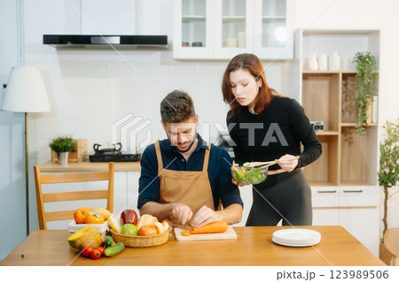 Discover a joyful couple preparing fresh vegetables, embracing healthy eating and teamwork in a vibrant kitchen Discover a joyful couple preparing fresh vegetables, embracing healthy eating and teamwork in a vibrant kitchen 123989506