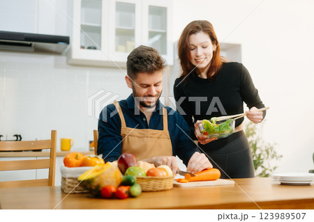 Discover a joyful couple preparing fresh vegetables, embracing healthy eating and teamwork in a vibrant kitchen Discover a joyful couple preparing fresh vegetables, embracing healthy eating and teamwork in a vibrant kitchen 123989507