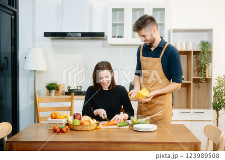 Discover a joyful couple preparing fresh vegetables, embracing healthy eating and teamwork in a vibrant kitchen Discover a joyful couple preparing fresh vegetables, embracing healthy eating and teamwork in a vibrant kitchen 123989508