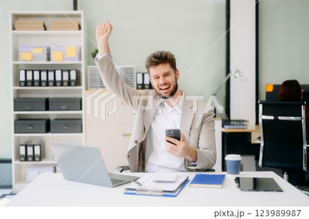 Young businessman working with working notepad, tablet and laptop documents talking on the smartphone Young businessman working with working notepad, tablet and laptop documents talking on the smartphone 123989987