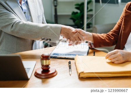 Judge and client shaking hands and lawyers discussing contract papers after adviced Judge and client shaking hands and lawyers discussing contract papers after adviced 123990667