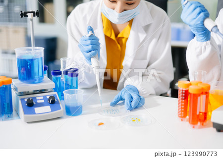 Young scientists conducting research investigations in a medical laboratory, a researcher in the foreground Young scientists conducting research investigations in a medical laboratory, a researcher in the foreground 123990773