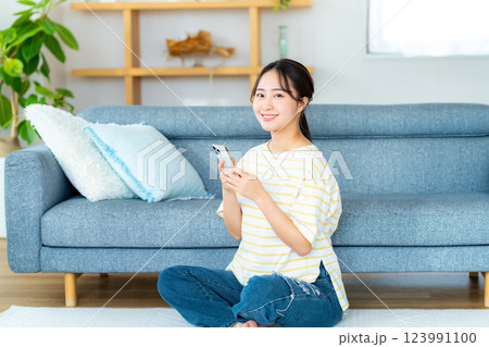部屋でスマホを操作する若い女性 部屋でスマホを操作する若い女性 123991100