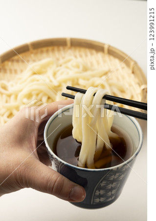 冷たいざるうどんを箸で持ち上げつゆに付ける 冷たいざるうどんを箸で持ち上げつゆに付ける 123991215