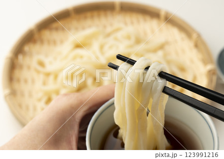 冷たいざるうどんを箸で持ち上げつゆに付ける 123991216