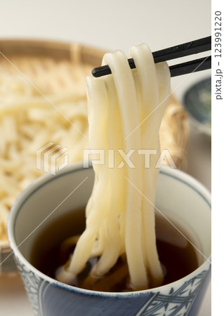 冷たいざるうどんを箸で持ち上げつゆに付ける 123991220