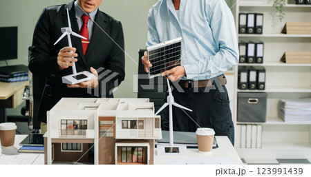 Architects in a business meeting, planning and discussing a modern building model, showcasing teamwork and creativity 123991439