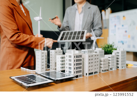 Team of diverse multiethnic businesspeople standing neare table looking at model of building from residential project. Team of diverse multiethnic businesspeople standing neare table looking at model of building from residential project. 123991552