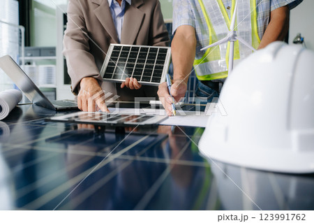 Two engineers collaborate on solar and wind energy, driving clean innovation and sustainability. A vision of teamwork Two engineers collaborate on solar and wind energy, driving clean innovation and sustainability. A vision of teamwork 123991762
