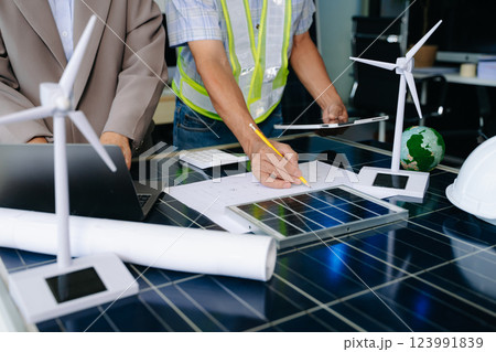 Two engineers collaborate on solar and wind energy, driving clean innovation and sustainability. A vision of teamwork Two engineers collaborate on solar and wind energy, driving clean innovation and sustainability. A vision of teamwork 123991839
