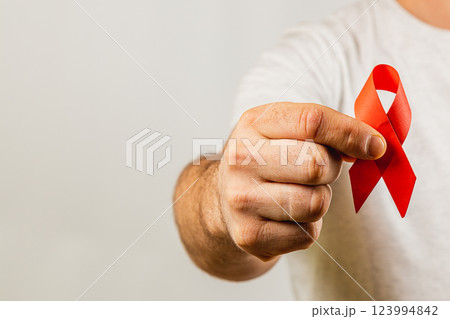 Individual holding red awareness ribbon symbolizing health advocacy efforts Individual holding red awareness ribbon symbolizing health advocacy efforts 123994842