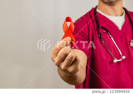 Medical professional holds red ribbon symbolizing HIV awareness during event 123994850