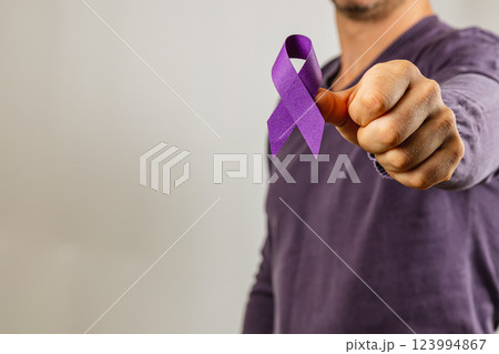 Individual holds purple ribbon to raise awareness for a cause Individual holds purple ribbon to raise awareness for a cause 123994867