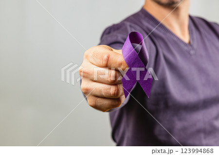 Person holding a purple ribbon to raise awareness for important causes 123994868