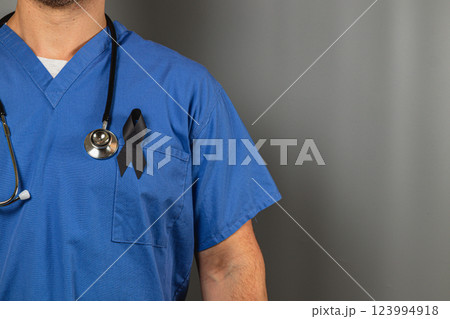 Healthcare worker wearing blue scrubs with black ribbon for mourning 123994918