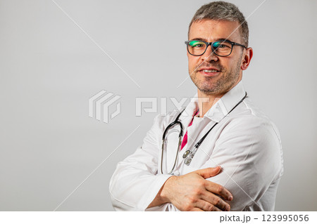 Doctor in white coat poses confidently for a professional portrait at clinic Doctor in white coat poses confidently for a professional portrait at clinic 123995056