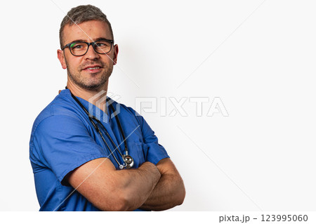 Medical professional in scrubs standing confidently against plain backdrop Medical professional in scrubs standing confidently against plain backdrop 123995060