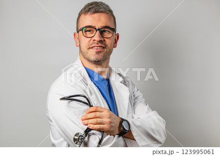 Medical professional in white coat holding stethoscope with a smile 123995061