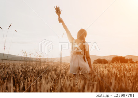 Woman wheat field. Agronomist, Woman farmer check golden ripe barley spikes in cultivated field. A woman is holding a bunch of wheat in her arms. 123997791