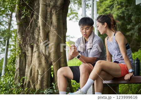 young asian couple using cellphone outdoors 123999616