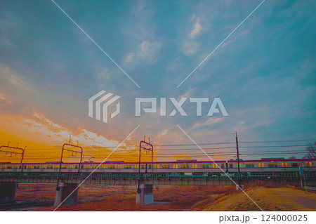 多摩市聖蹟桜ヶ丘駅から中河原駅を繋ぐ京王線の橋を夕暮れ時に渡る電車の写真 124000025