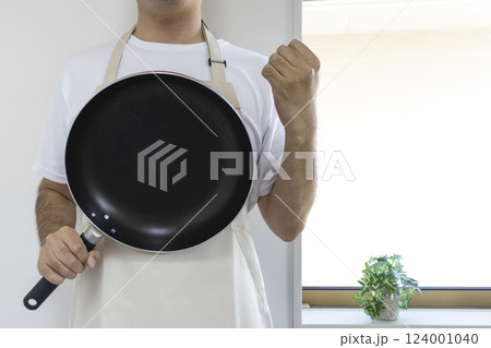エプロンを付けフライパンを持ちガッツポーズしている男性（顔無し、日本人、30代） 124001040
