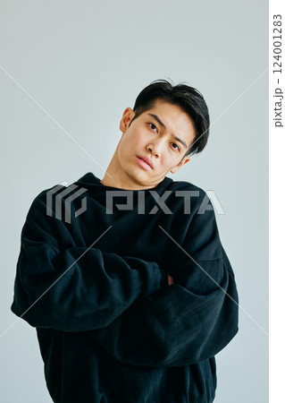 腕組みをしながら首をかしげる20代の若い男性 124001283