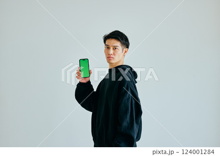 スマホを持つ20代の若い男性 グリーンバック スマホを持つ20代の若い男性 グリーンバック 124001284