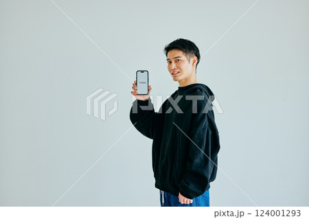 スマホを持つ20代の若い男性 新NISA スマホを持つ20代の若い男性 新NISA 124001293