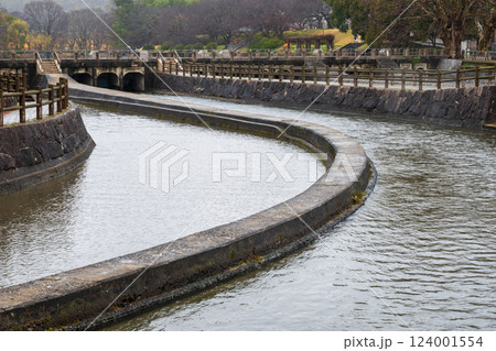 日本の岡山県倉敷市の水路のある公園の雨天の風景 124001554