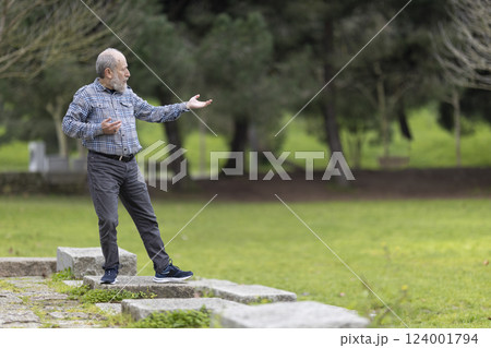 Senior man practicing tai chi chuan in a public park 124001794