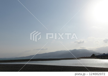 春のかすみがかった青空となだらかな山と夕方の光を反射する海辺の河口 春のかすみがかった青空となだらかな山と夕方の光を反射する海辺の河口 124002072