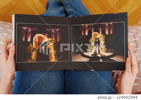 Female hands flipping through a photo book with wedding photos 124002994