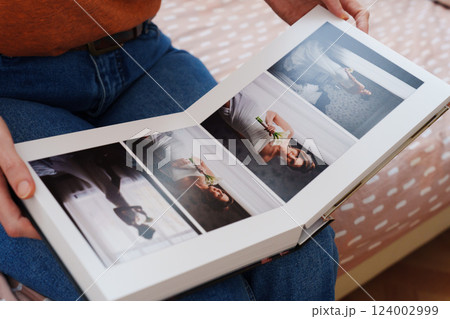 Female hands flipping through a photo book with wedding photos 124002999