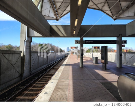 Street platform in Reston, Virginia, with subway train tracks and cityscape behind wooden fence with information board, no people Street platform in Reston, Virginia, with subway train tracks and cityscape behind wooden fence with information board, no people 124003403