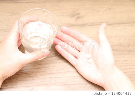 内服薬1錠を飲もうとする男性の手とグラスの水 内服薬1錠を飲もうとする男性の手とグラスの水 124004415
