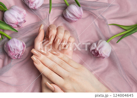 Woman showing nude manicure on pink background with tulips 124004645