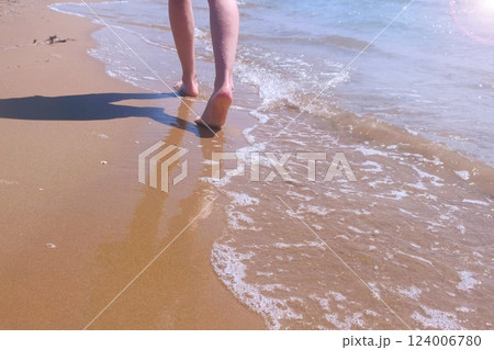 Barefooted woman tourist walks in water on sea sand beach, legs closeup. Barefooted woman tourist walks in water on sea sand beach, legs closeup. 124006780